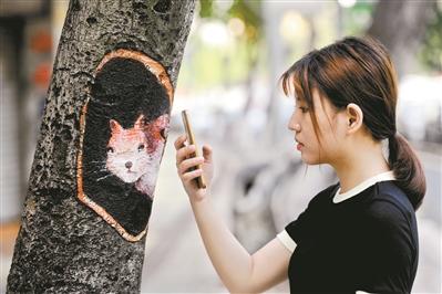 树上涂画的松鼠图案引来美女观看拍摄。