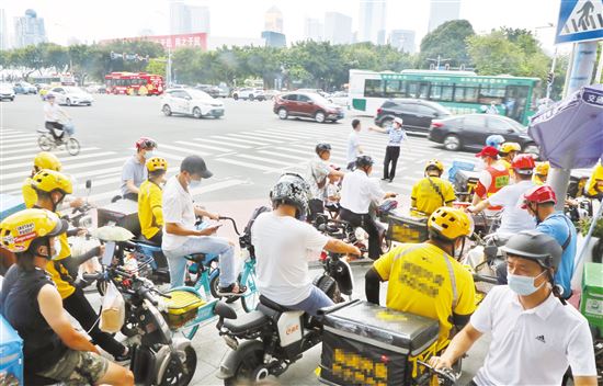 天河体育中心附近的十字路口人行横道上,电动车数量不少,大部分车主都佩戴了头盔。