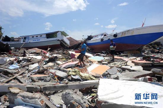10月5日，在印度尼西亚中苏拉威西省栋加拉县，灾民在房屋废墟中寻找可用物品。 新华社发（阿贡摄）