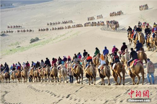 国庆长假期间，国际旅游名城甘肃敦煌著名景区鸣沙山月牙泉旅游迎来“高峰模式”。据统计，10月3日，该景区接待中外游客达到3万人次，掀起金秋敦煌旅游新高潮。王斌银 摄