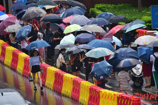 高考首日，广州大雨，在执信中学考点，大门外，家长在雨中盯着大门内等待。 记者 邓勃 摄