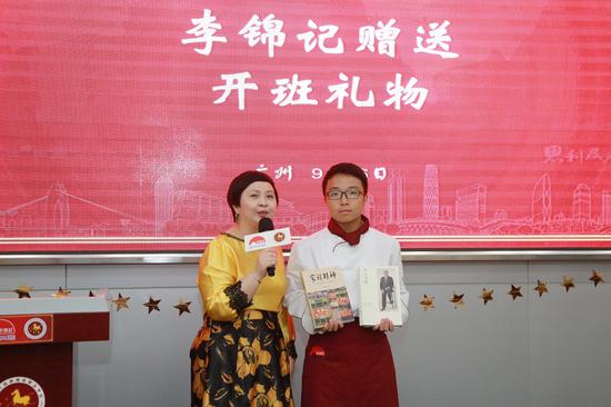 赖洁珊总监为包县彬同学送上《家族精神》与《李文达传》，鼓励新生牢记使命