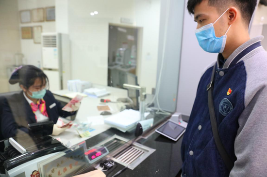 (遂溪县税务局号召党员干部开展爱心捐款活动,获得战疫善款约3万元,图为税务青年徐文在银行转账汇款)