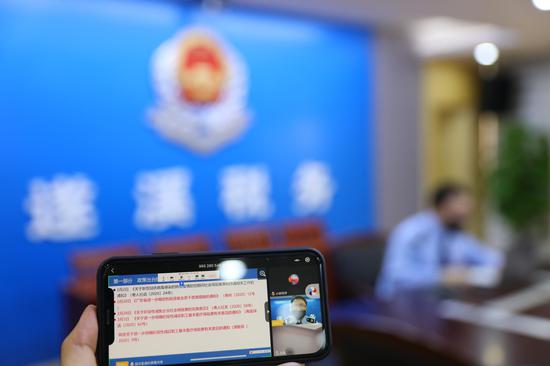 (图为税务青年梁洲鹏在税费优惠政策直播间中解读社保费政策)