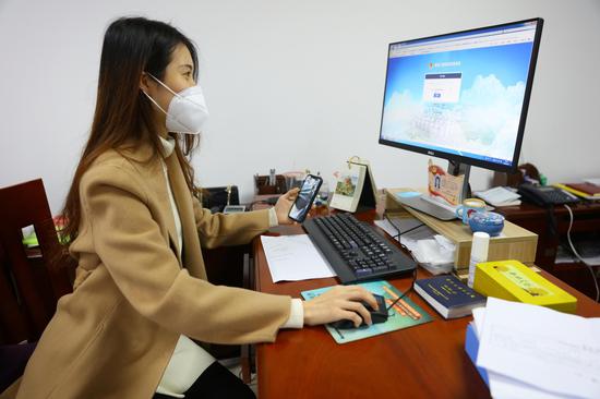 (图为税务青年李莹莹利用“金税三期税收管理系统”进行数据分析)