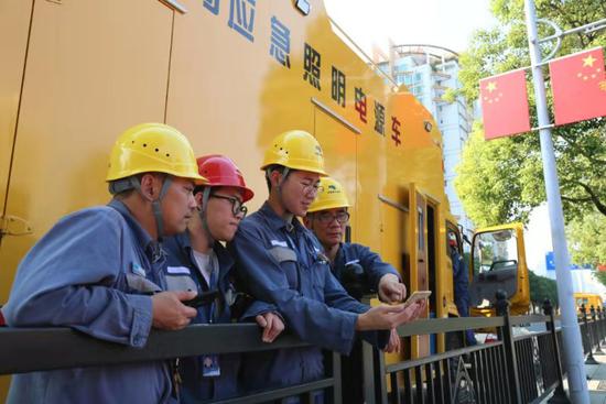 南方电网广州海珠供电局保供电人员在现场用手机观看新中国成立70周年庆祝活动。