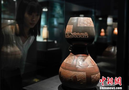 发布会现场的坭兴陶小型展览,观众正在欣赏一尊“窑变”的作品 杜洋 摄