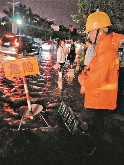 暴雨夜,长安相关部门的工作人员在沙井盖被冲开的位置设立警示标志,提醒行人和驾车司机避让。广州日报全媒体记者刘满元 通讯员莫艳芬摄