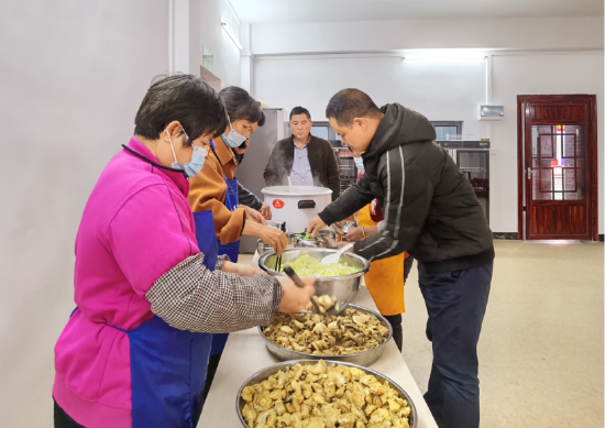 图为村党总支部书记陆飞红(右)在为老人上菜。只要有空,他经常到乐膳馆厨房转转。