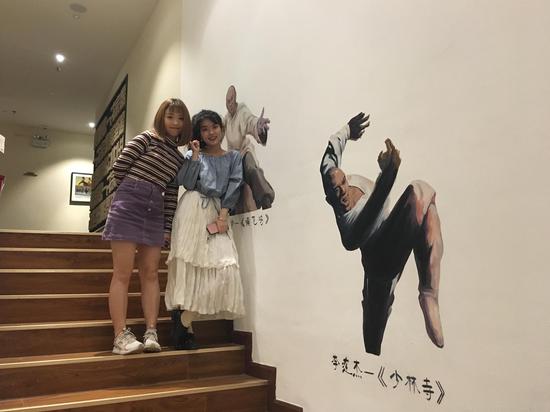 “穗子怪怪”和“壹不正经KK”在艾薇吾系酒店的功夫名人涂鸦墙合影留念