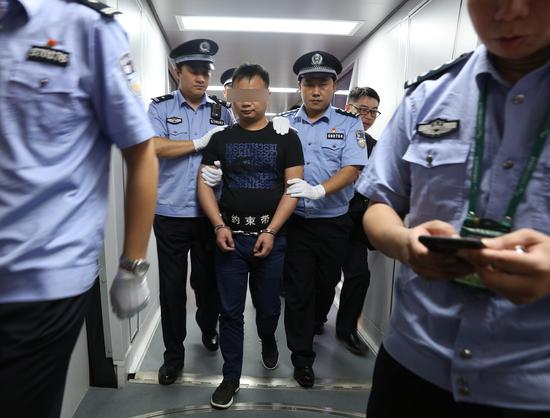 7月27日晚,潜逃十年的“红通”嫌疑人王某被海关缉私警察押解走下飞机。(赵立阳 摄影)