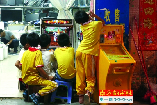↑↑夜晚下的南屏村，小学生围在商店门口的游戏机前玩游戏。