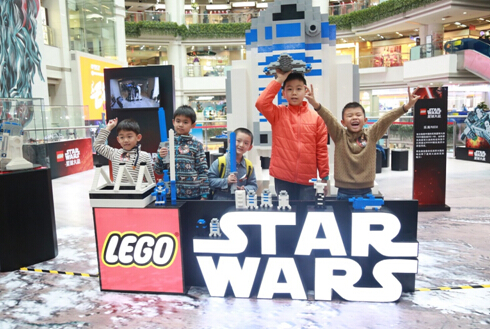 小朋友在巨型乐高星球大战R2-D2模型前展现自己的创意拼搭作品