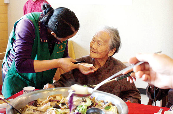 社工在喂老人吃斋菜。