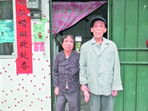 81岁的陈桂芳牵着77岁的老伴张瑞心在住房前留影。