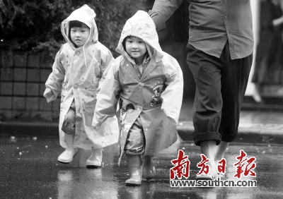 在广州东湖西路，两名小朋友在雨中奔跑。南方日报记者 李细华摄