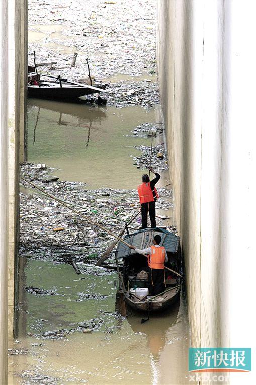 ■工作人员用竹竿将垃圾往岸边推去，岸边则有两台钩机将小船推来的垃圾勾起运上斗车。