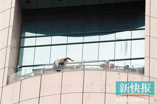 ■昨日下午，罗某趴在天娱广场15楼露台的玻璃上，半边身子悬在空中。随后罗某被警方成功解救。