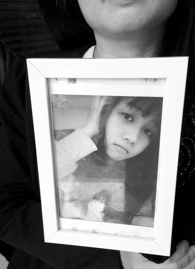 前日下午，小华的母亲站在涉事卫生所门前捧着女儿生前的照片