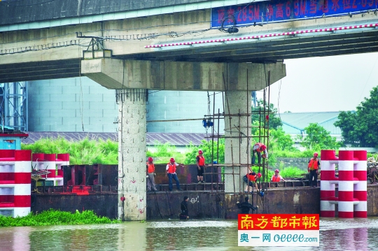一条维修船停在受损桥墩旁，工人在维修。