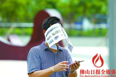 昨日我市天气炎热,禅城区建新路上一位市民用广告传单遮挡烈日
