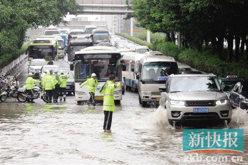 昨天清晨,暴雨导致广园路科韵路立交附近路段水浸严重,双向车行缓慢,交警站在水中疏导交通。 新快报记者 毕志毅/摄