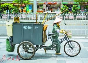 2015年7月,环卫工人在高温下推着垃圾车前行