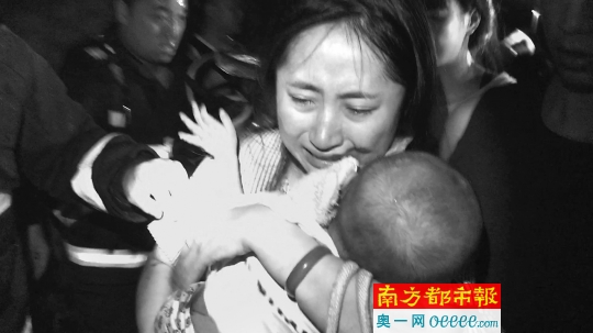 佛山南海一居民楼起火，一名婴儿被救出，在一楼等待的母亲哭着接过了孩子。 消防供图