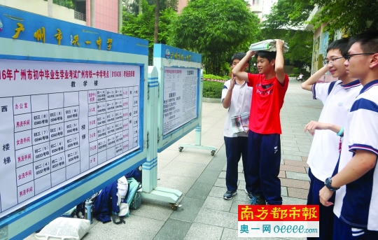 6月16日，广州铁一中学中考考场，考生顶着书本看考场安排表。南都记者 冯宙锋 摄
