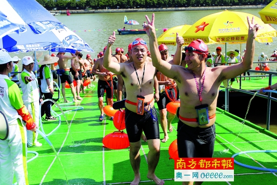 参加横渡的泳手们走上岸，比出胜利手势。

    摄影：南都记者 邹卫 马强 陈志刚

    实习生 胡弘智
