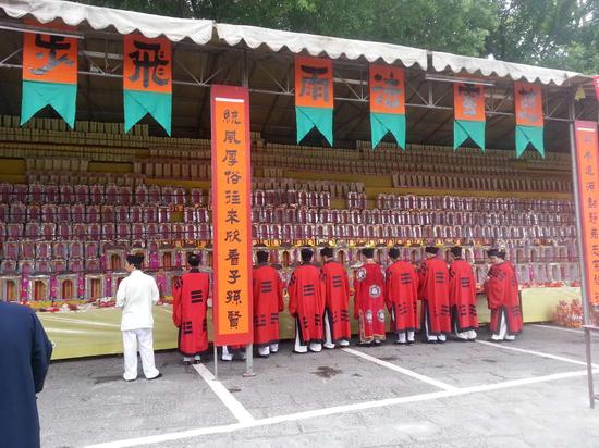 身穿红色道服的法师站在安放花牌及字牌的祭坛前方诵经，祈祷死难者能够早日登步仙界。