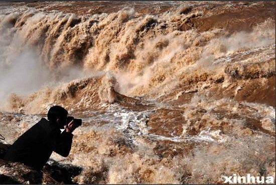 一名摄影者在山西吉县黄河壶口瀑布拍摄“桃花汛”美景。（新华社记者 吕桂明 摄）