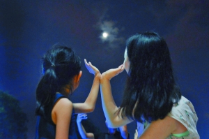 花城广场，一位妈妈和女儿做着捧月的动作庆祝中秋节。