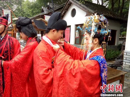 50个民族70对情侣“单身节”在广东东莞凤岗镇举行多民族特色集体婚礼。图为身穿民族特色服装的新人们在台下互相帮忙整理服装。　安致标 摄
