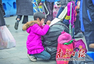 趁等车间隙，一名小朋友正在认真做寒假作业。南方日报记者 张由琼 罗斌豪 摄