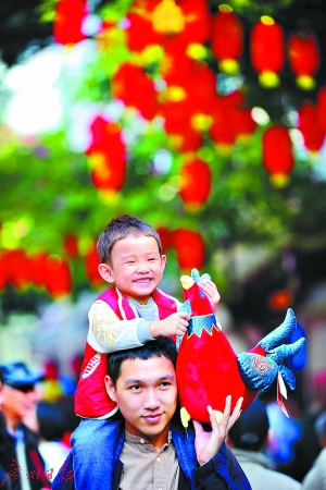 孩子抱着鸡公仔，父亲带孩子逛花市。 　　广州日报记者王燕 摄