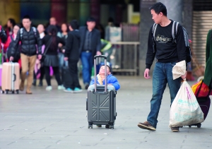 广州火车站，小孩推着行李箱跟着大人出站。信息时报记者 陈引 摄