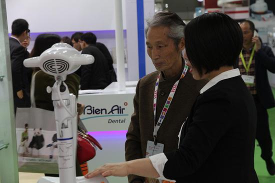 普洋科技展位工作人员为参会者介绍牙齿冷光美白仪