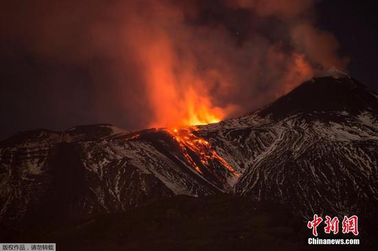 当地时间4月11日，意大利埃特纳火山持续喷发，被白雪覆盖的火山与山下码头灯光相映成辉。