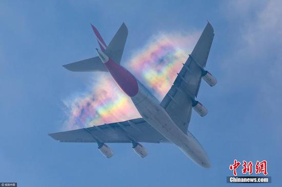 英国伦敦，英国摄影师亚当·格雷（Adam Gray）在位于伦敦南部的家中拍到了罕见的“飞机彩虹”，照片中飞机身后跟随着七色彩虹云，令人惊奇万分。