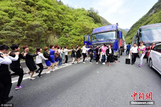 4月22日10时多，西安，在西汉高速户菜出口东边，遭遇小范围的堵车，近百辆大小不一车辆滞留等待长约半个多小时，一群从江苏总部学习返回四川的乘客，为驱散堵车心慌、心烦，跳起舞蹈解闷，顿时，不少其它车辆乘客加入欢快舞蹈人群中。 图片来源：视觉中国