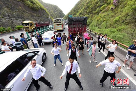 4月22日10时多，西安，在西汉高速户菜出口东边，遭遇小范围的堵车，近百辆大小不一车辆滞留等待长约半个多小时，一群从江苏总部学习返回四川的乘客，为驱散堵车心慌、心烦，跳起舞蹈解闷，顿时，不少其它车辆乘客加入欢快舞蹈人群中。 图片来源：视觉中国