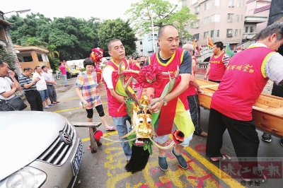 龙舟队的队员们合力将龙舟抬到河涌边,再把龙头装上。