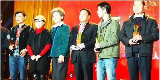 周崇练(右一)与荣获第三届全国村歌大赛十大金曲作词金奖的部分获奖者在北京人民大会堂接受著名歌唱家李谷一颁奖