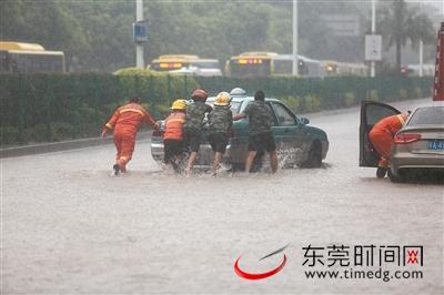 南城宏图路与城市风景街十字路口，一辆出租车在水中熄火，救援人员将车推出积水 东莞时报记者 陈栋 陈帆 实习生 谭智棋 摄