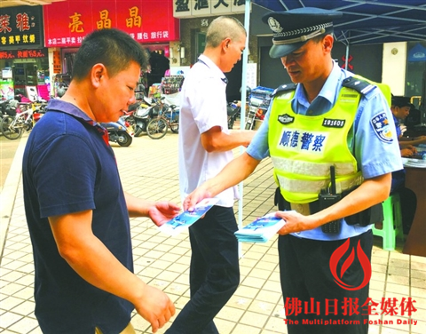 在容桂宏骏广场步行街，民警向过往市民派发防范电信诈骗宣传单张。/佛山日报记者唐格桢摄