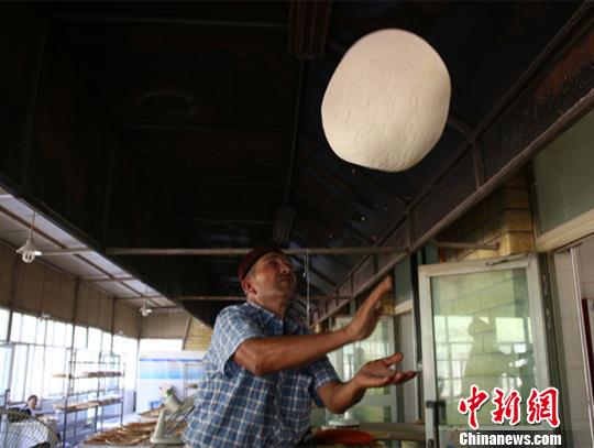 图为打馕师傅正在演示“飞”馕。