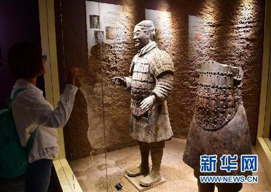 观众在西安秦始皇帝陵博物院举办的“留住色彩——陶质彩绘文物保护成果展”上参观修复中的兵马俑