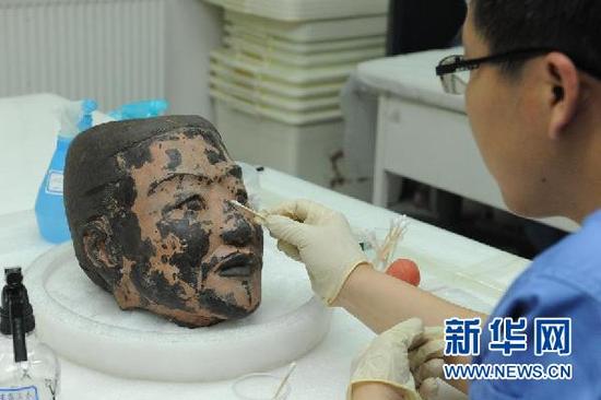 工作人员在西安秦始皇帝陵博物院文物保护实验室内对俑头进行清理（2012年6月9日摄）