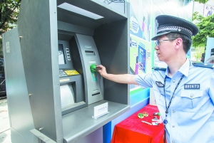 ①活动现场，警察演示不法分子如何将侧录器安装在ATM柜员机上。